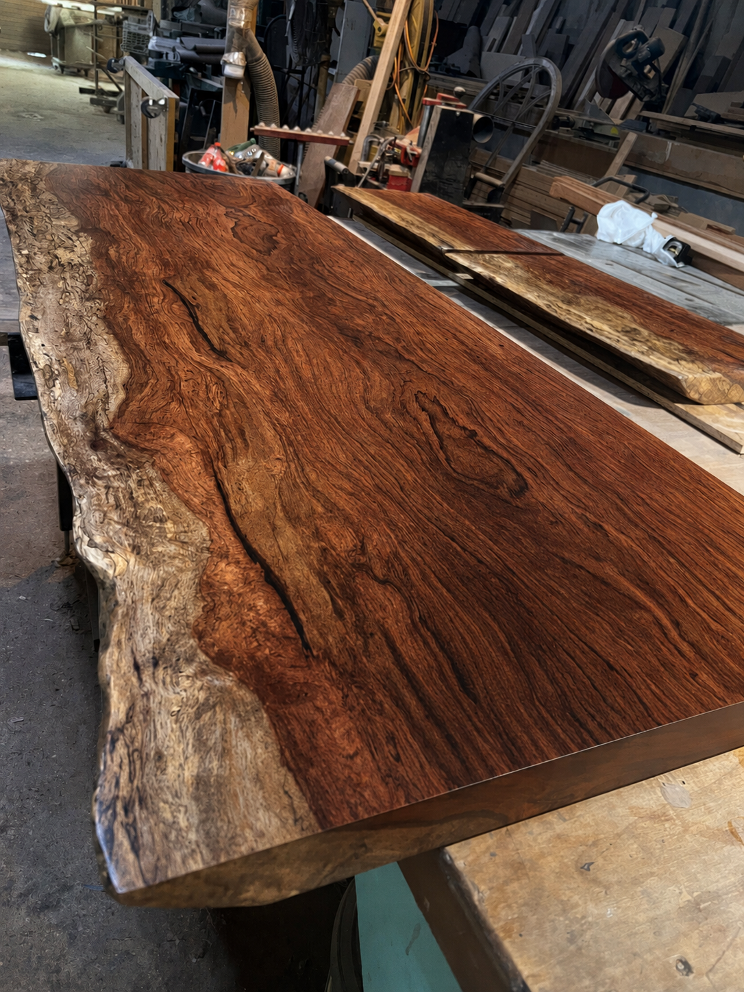 Finished live-edge wood slab showing rich natural grain in the DCW workshop